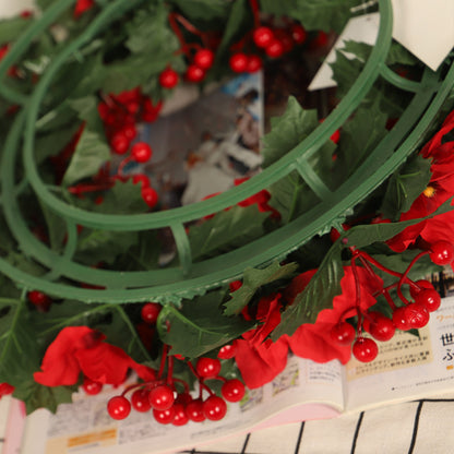 Corona navideña roja con hojas de tridente verde